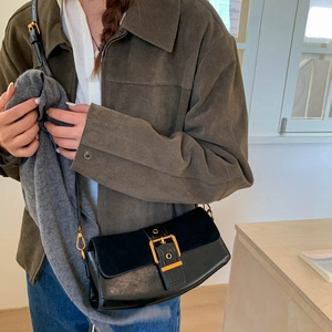Fashionable black matte patchwork shoulder bag with gold buckle on a model in sunlight