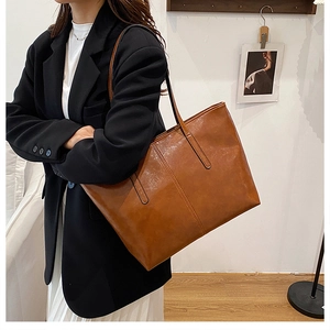 Brown faux leather tote bag styled with black blazer for a chic autumn look