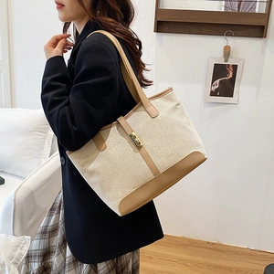 Minimalist canvas tote bag with brown leather trim and golden metal lock detail