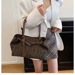 Detailed view of leopard print tote bag with brown leather straps shown on a model