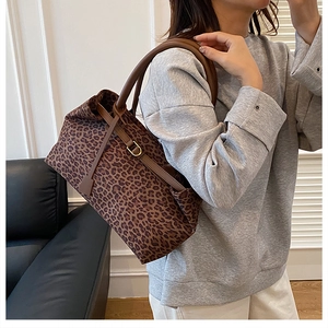 Detail of leopard print tote bag featuring brown leather straps and gold metal clasp hardware