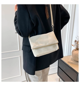 Modern cream white crossbody bag with gold zipper and foldover flap shown on model
