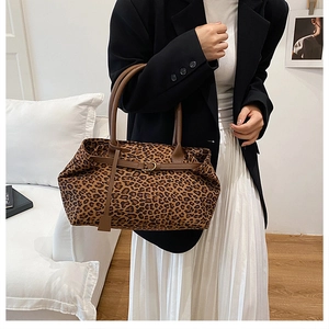 Chic leopard print tote bag with brown leather handles and gold buckles worn by model