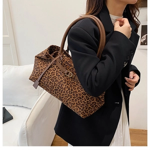 Detail of leopard print tote bag featuring textured fabric and brown leather handles