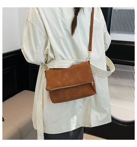 Detail view of caramel brown leather crossbody bag showing size and drape on white shirt