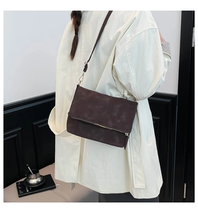 Detail of dark brown matte messenger bag with zipper accent and crossbody strap