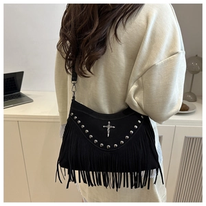 Détail d'un sac à main gothique noir avec rivets, franges et croix métallique