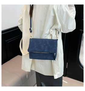 Detail of navy blue crossbody bag with gold zipper and minimalist flap design