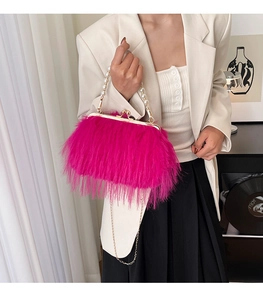 Dettaglio borsa fucsia in piume di tacchino con manico di perle e catena d'oro