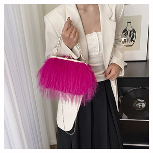 Borsa da sera in piume fucsia con manico di perle e catena d'oro indossata da modella