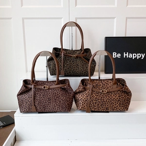 Three leopard print tote bags in brown and tan with leather handles and metal buckles