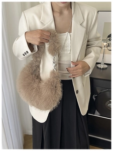 Detail of light brown faux fur crescent bag with heart pendant and silver chain strap