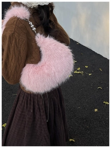Detailed view of a pink faux fur crescent shoulder bag with silver heart chain strap