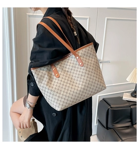 Close-up of vintage brown pattern tote bag with leather strap and gold rivet details