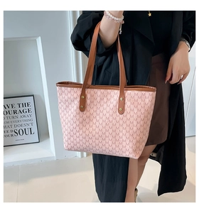 Detailed view of large tote bag with pink M-letter pattern and brown leather straps