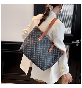 Detail of vintage plaid patterned tote bag with brown leather straps and gold rivets