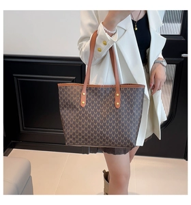 Detailed view of brown tote bag with M-pattern print and leather straps on model