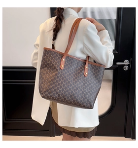 Detailed view of coffee brown tote bag featuring M-letter pattern and gold metal rivets