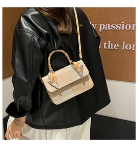 Detail of beige flap bag with sequin texture and silk scarf wrapped around handle