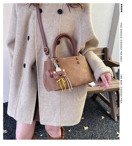 Dettaglio della borsa tote vintage in pelle marrone con borchie e ciondolo a forma di orso