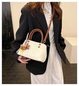 Modella che indossa una borsa a secchiello crema e marrone con ciondoli orsetto