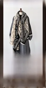 Detail of winter paisley pashmina shawl featuring black and beige patchwork with tassels
