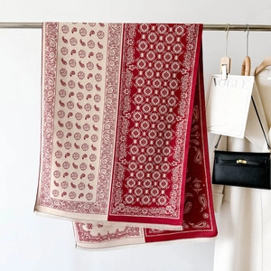 Detail of red paisley shawl with bohemian motifs and fringe edges on a metal hanger