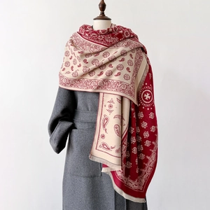 Red and beige paisley jacquard winter shawl with fringe on a gray wool coat