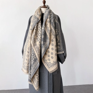 Detail of soft paisley shawl featuring beige and grey patterns with delicate short tassels