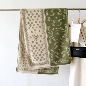 Detail of olive green and beige paisley shawl featuring delicate frayed edges and pattern
