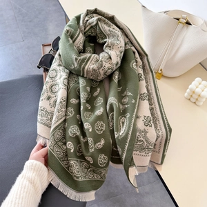 Detail of soft paisley shawl with tassels showing the dark green and beige fabric texture