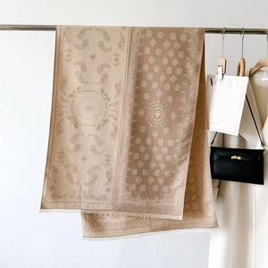 Detail of paisley pattern shawl with fringe edge and designer logo hanging on a rack