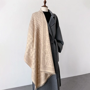 Detail of beige paisley cashmere scarf showing intricate weave and tassel fringe textures
