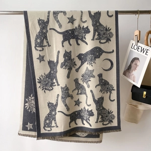 Detailed knit texture of beige shawl with dark gray cat and star jacquard patterns
