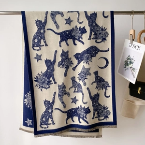 Navy blue cat and star moon patterned knit shawl with fringe on a metal rack