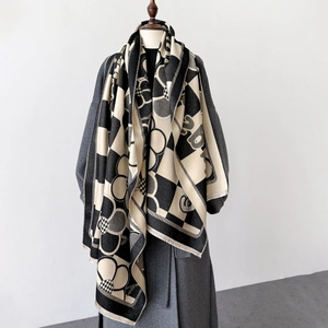 Detail of checkered and floral knit scarf with fringed edges on a grey wool coat