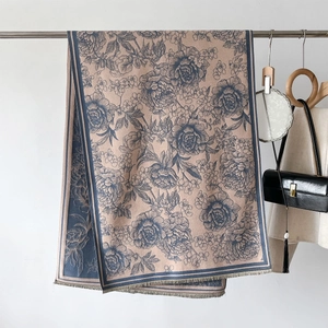 Detail of elegant beige cashmere-feel shawl with blue floral patterns and tassel edges