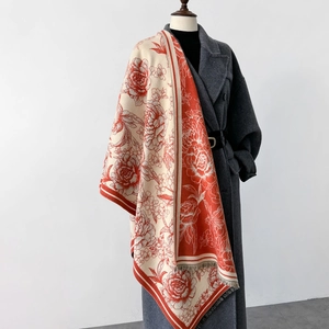 Close-up of beige cashmere scarf with orange peony floral patterns and fringe details