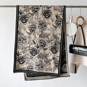 Detail of beige cashmere scarf with black peony floral patterns and fine fringe