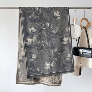 Detailansicht eines dunkelgrauen Winterschals mit Ahornblatt-Print und Fransen am Ständer