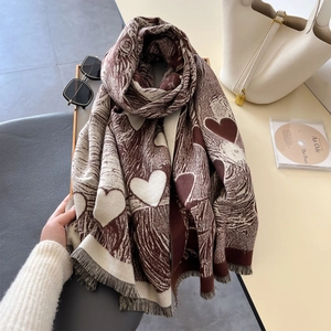 Dettaglio di una sciarpa jacquard a motivi di cuore con nappe marroni e color crema