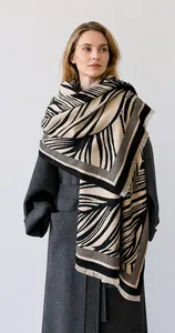 Close-up of thick winter scarf featuring abstract leaf patterns and fringe detail