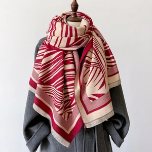 Thick warm scarf with red and beige geometric stripes and tassels on a mannequin