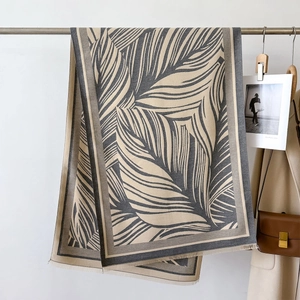 Detail of grey and white reversible scarf with palm leaf pattern and fringe edges