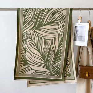 Detail of green leaf pattern warm scarf with tassel edges on a boutique display