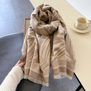 Detail of warm scarf showing earth-tone geometric patterns and soft fringe edges