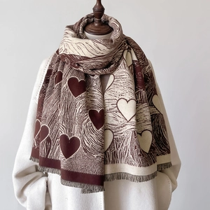 Sciarpa con motivo a cuore marrone e beige con frange su cappotto bianco invernale