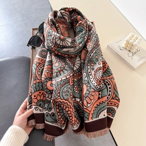 Détail d'un châle vintage à motif paisley avec franges près de lunettes et livre