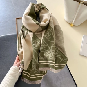 Close-up of green and cream plaid scarf with fringe tassels next to white handbag