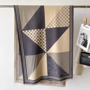 Detailed view of a geometric pattern scarf with fringe and modern artistic knit texture